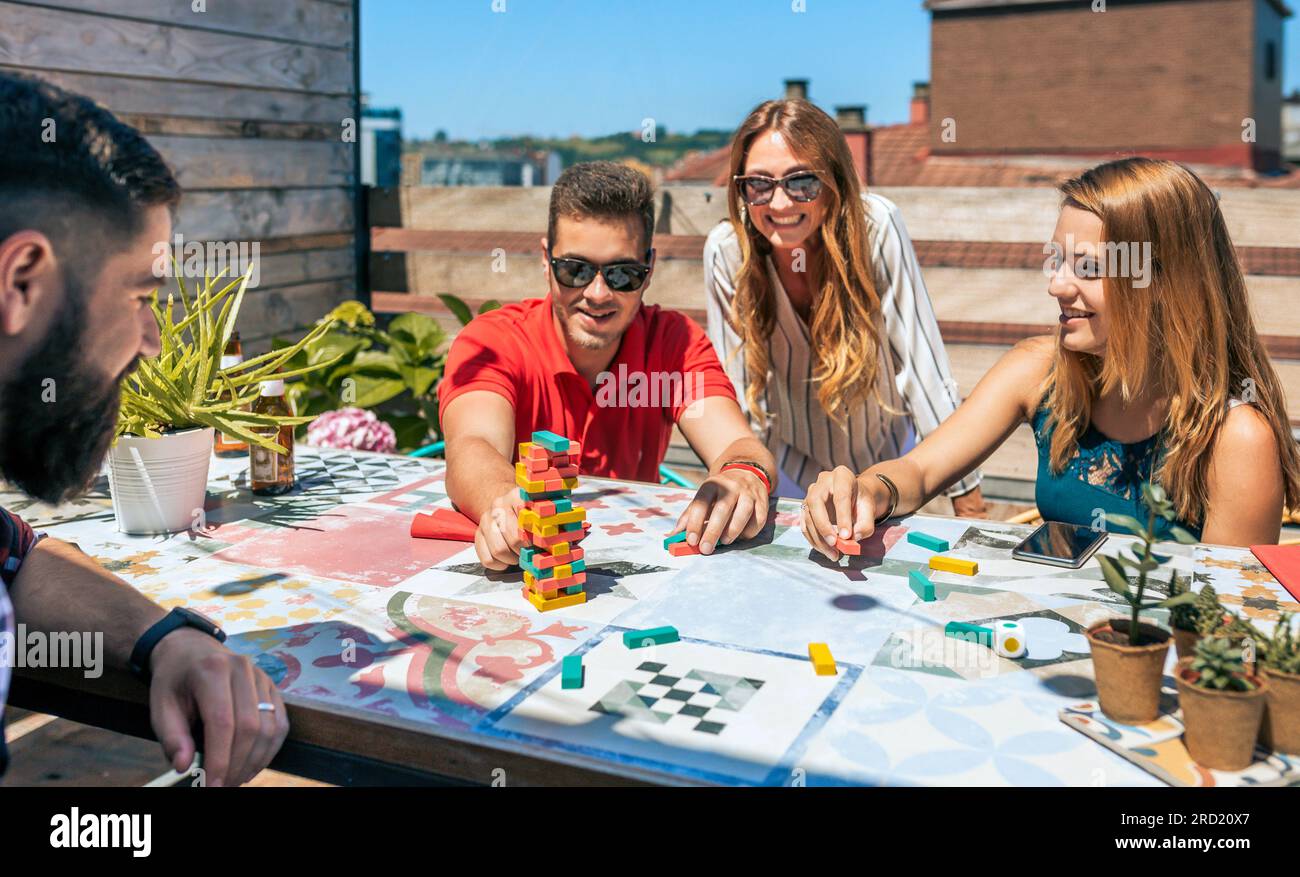 Group of happy office workers playing with jenga game on terrace in a coffee break Stock Photo