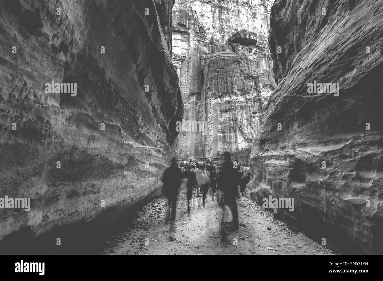 Group of people between sandstone rocks at narrow path in Petra, Jordan, black and white Stock Photo