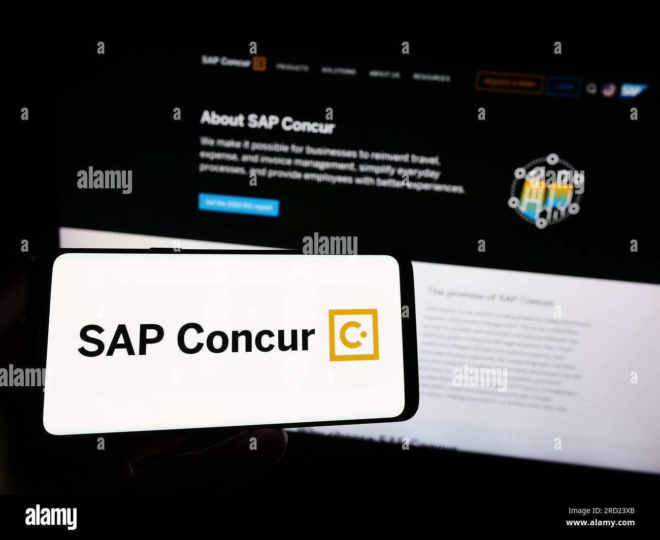 Person holding smartphone with logo of expense management software SAP Concur on screen in front of website. Focus on phone display. Stock Photo
