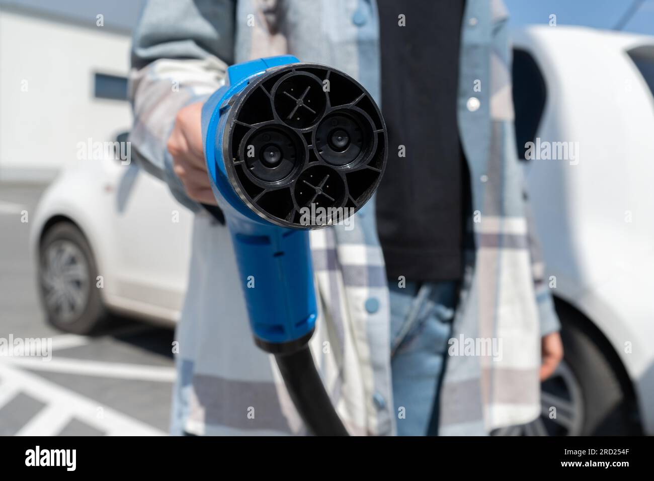 Woman holding fast charging socket CHAdeMO. Connector plug for electric vehicle battery at EV station, direct current DC. Plugging in car charger. Stock Photo
