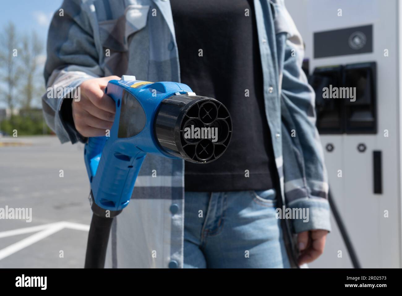 Woman holding fast charging socket CHAdeMO. Connector plug for electric vehicle battery at EV station, direct current DC. Plugging in car charger. Stock Photo