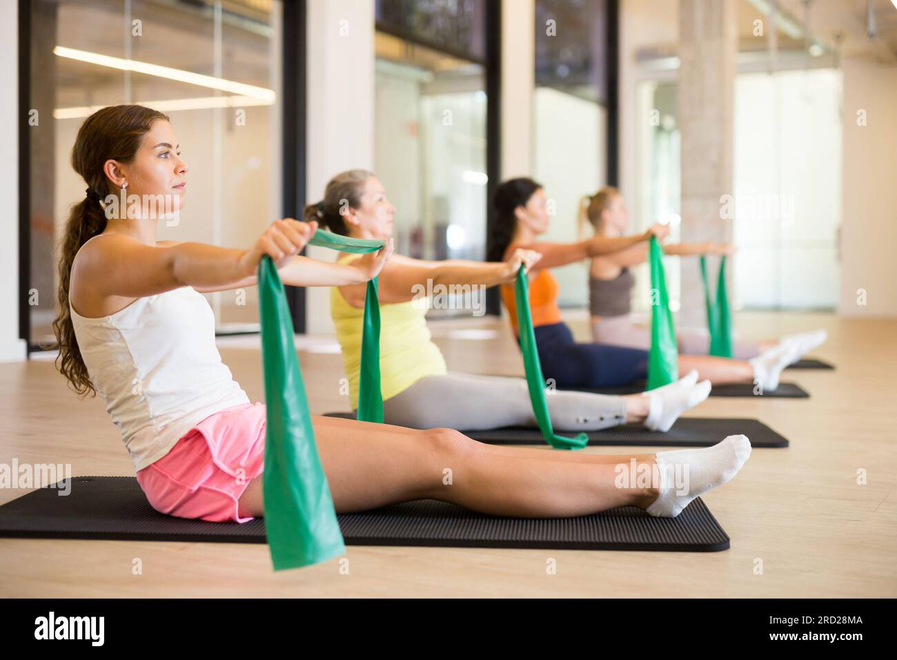 Women are doing stretching exercise with green resistance bands