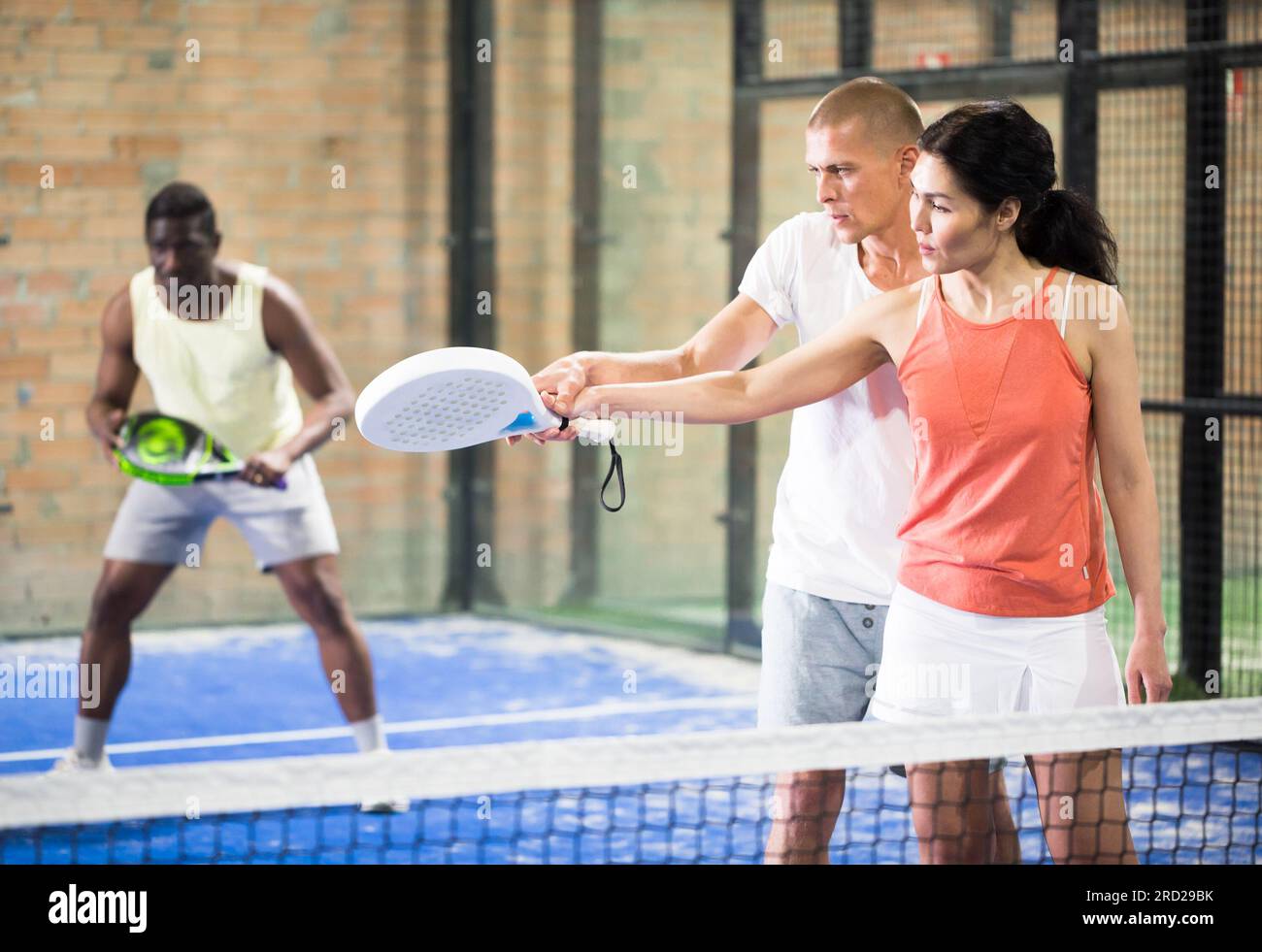 Man teaching woman to hold paddle racquet on indoor court Stock Photo ...