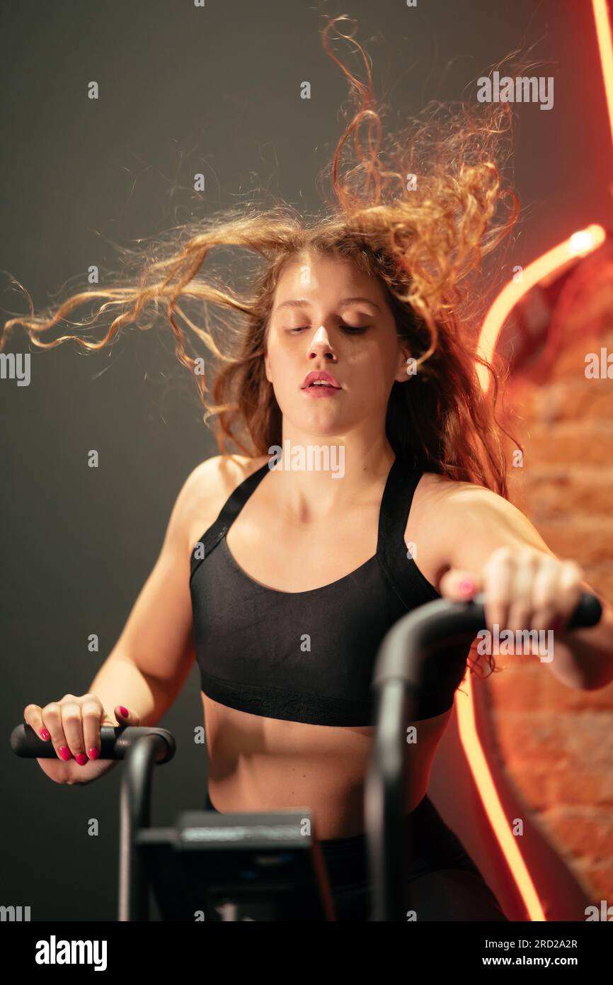 female running on elliptical orbitrek machine in fitness gym Stock