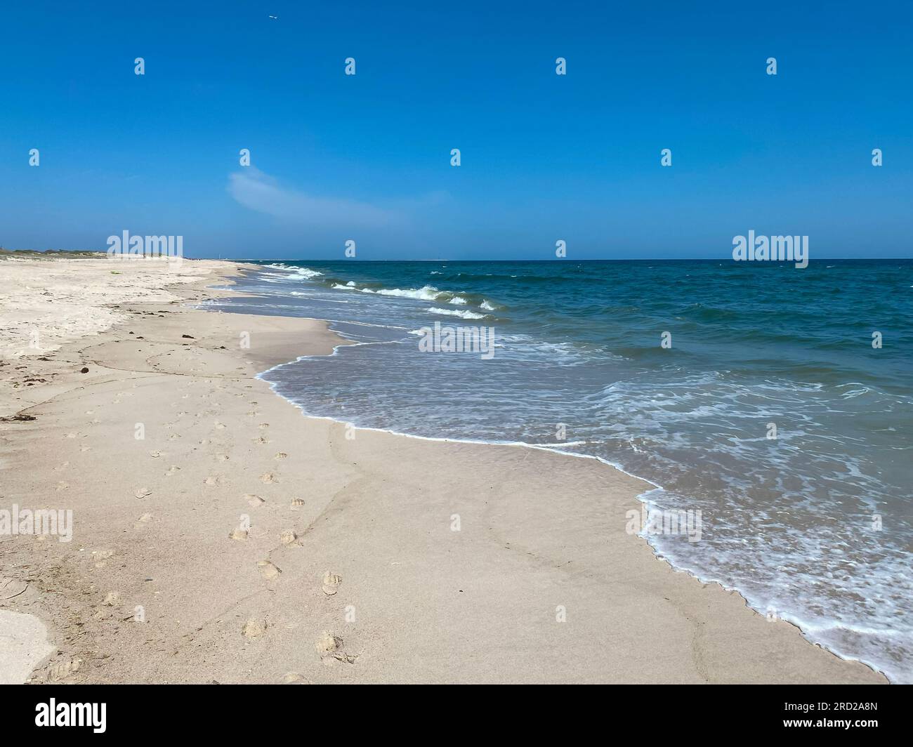 Footprints on an empty beach by the waters edge on the coast of Long Island New York. Stock Photo