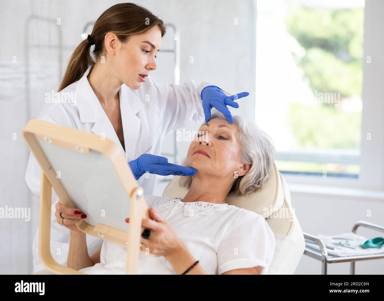 Skinologist Setup Cosmetologist with gloves preparing patient to skin care procedure in ...