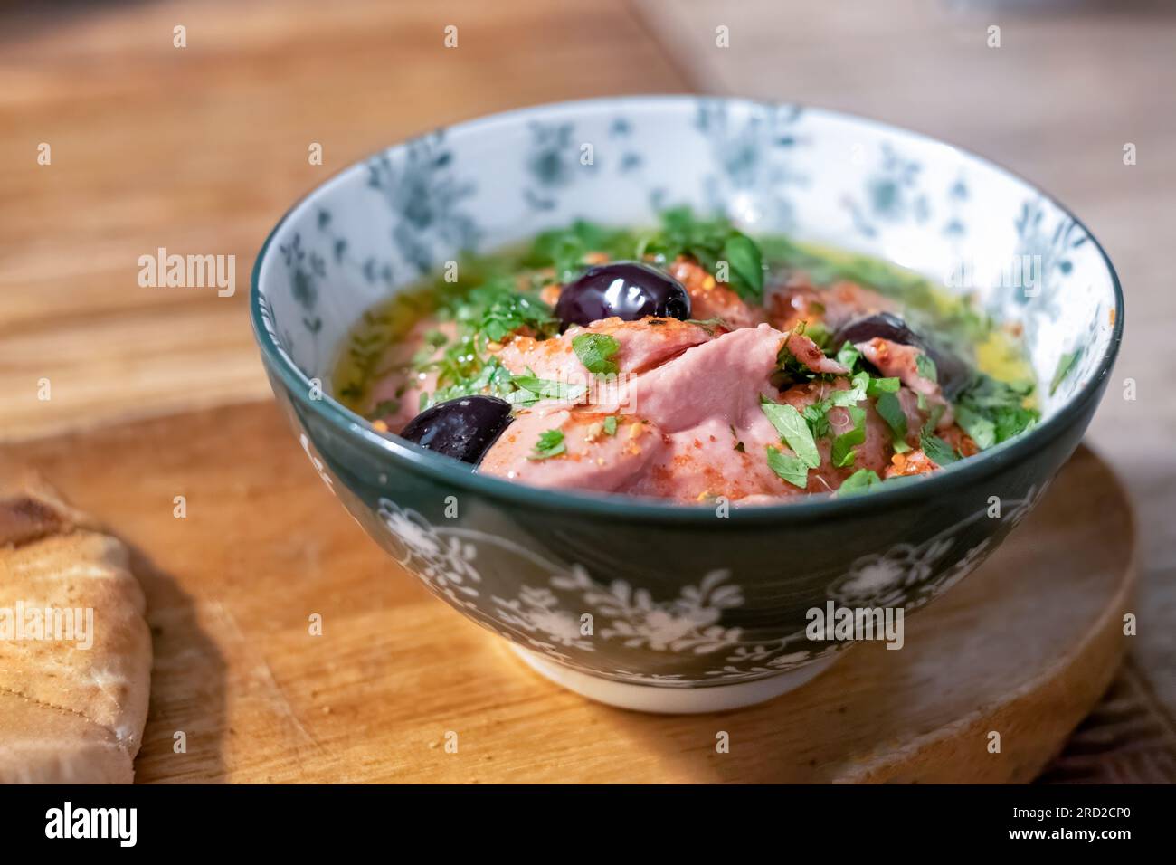 A single Tapas portion of Beetroot hummus served in a bowl with Black Olives and a herb dressing in a Tapas bar. Stock Photo