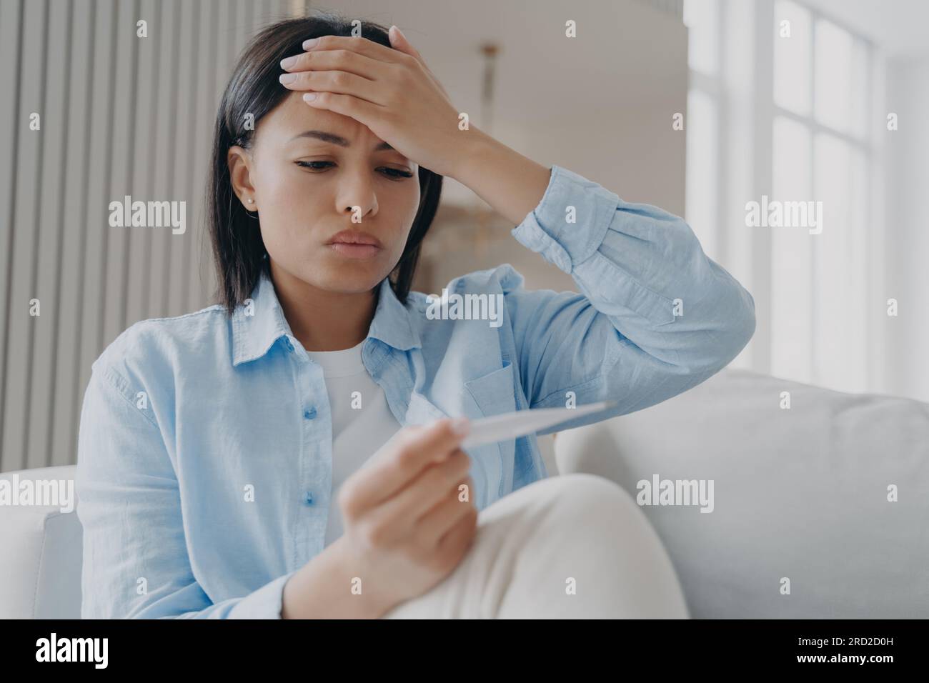 Unhealthy young woman holds electronic thermometer measure temperature