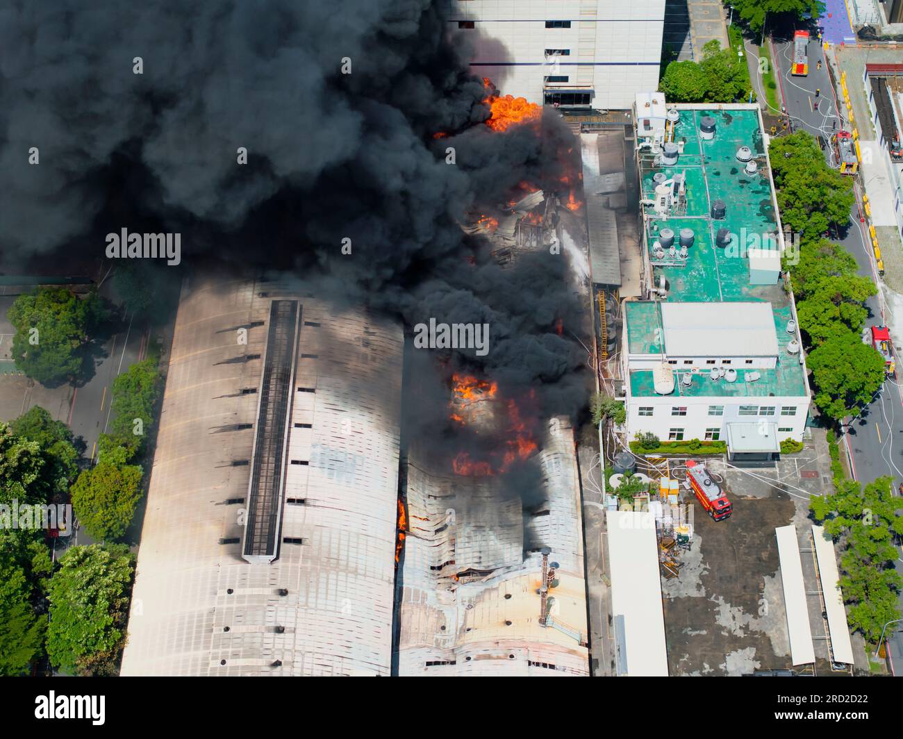 Aerial view of Fire in industrial building. Multi-storey concrete hangar with flames. Factory emergency concept. Stock Photo