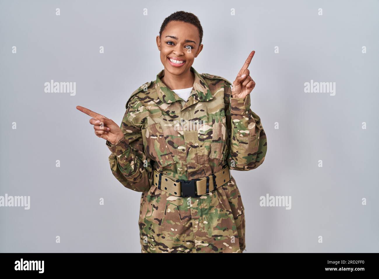 Beautiful african american woman wearing camouflage army uniform smiling confident pointing with fingers to different directions. copy space for adver Stock Photo