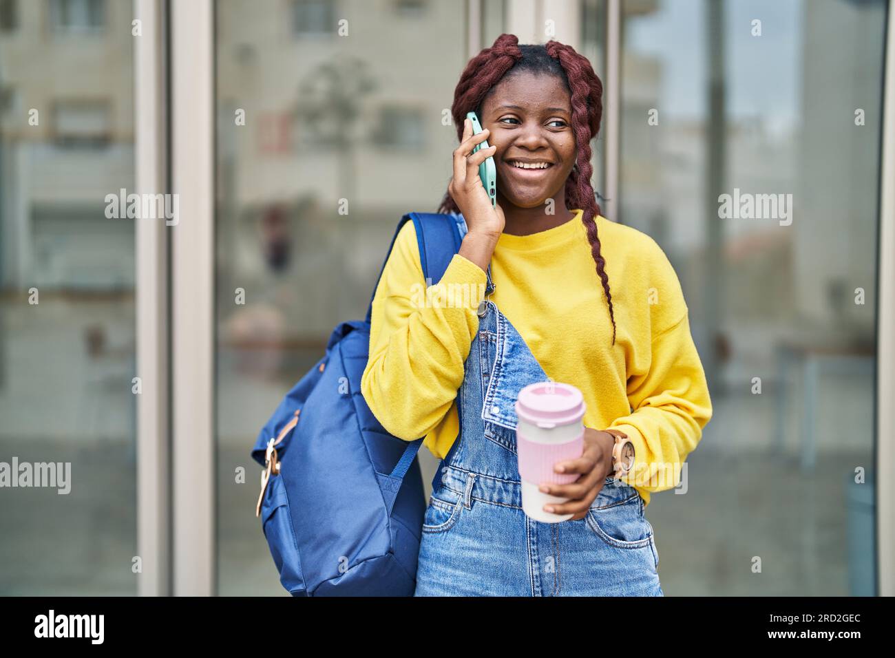 African american woman student talking on smartphone drinking coffee at ...