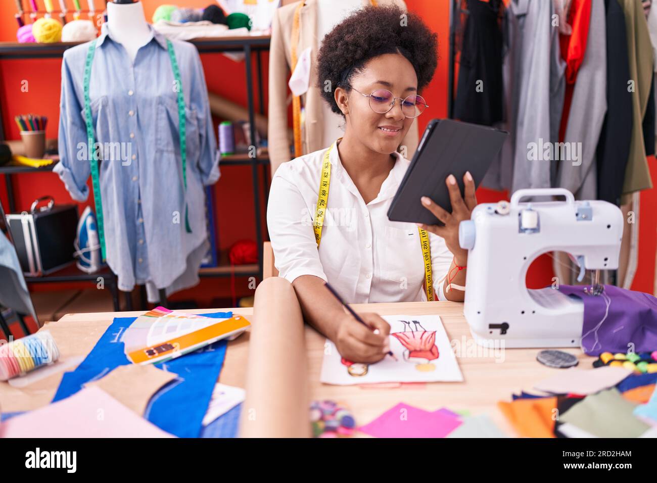 African american woman tailor using touchpad drawing clothing design at ...