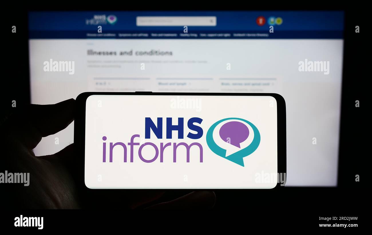 Person holding cellphone with logo of Scottish health information service NHS inform on screen in front of webpage. Focus on phone display. Stock Photo