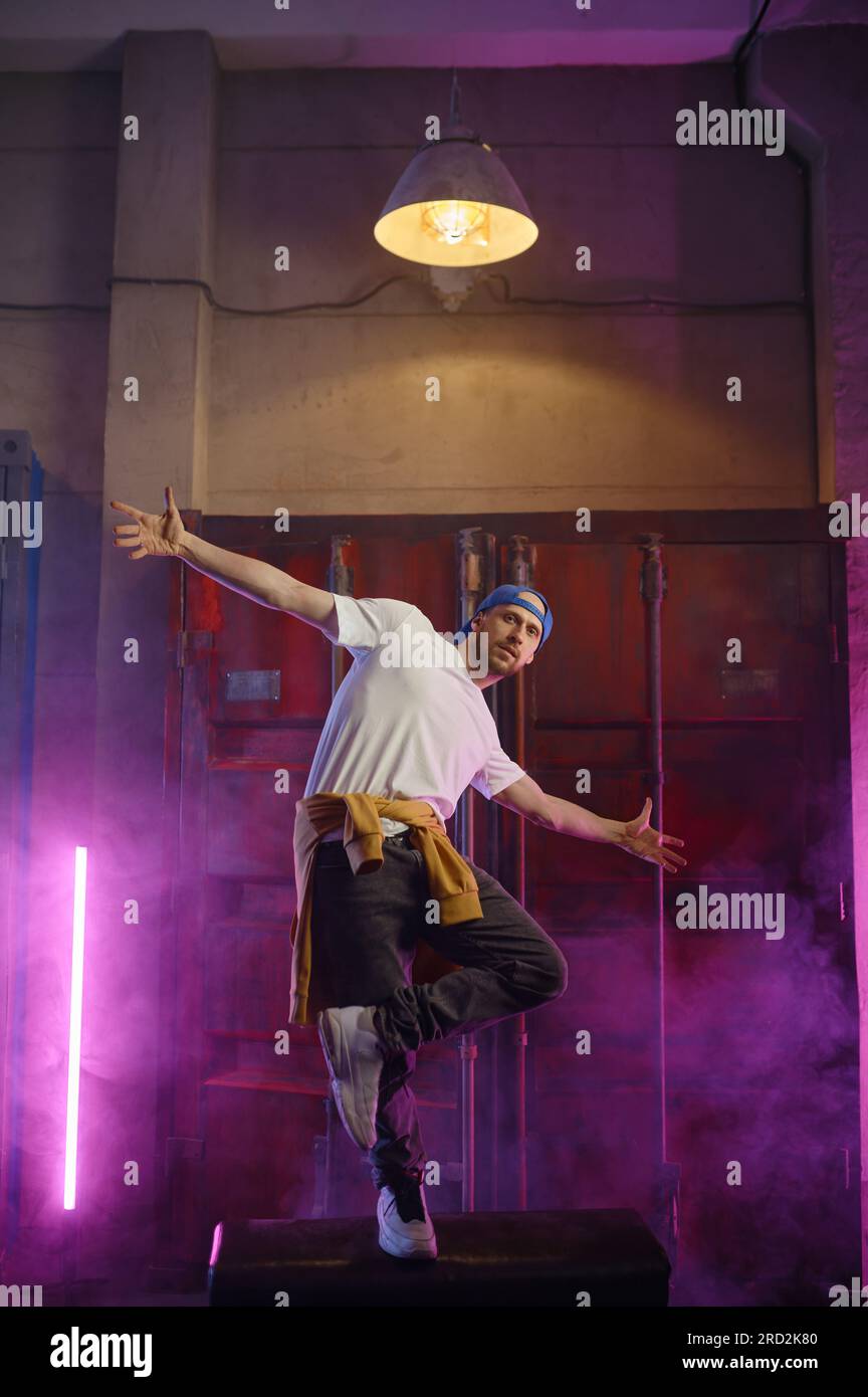 Young guy hiphop performer break dancing in neon club lighting Stock Photo