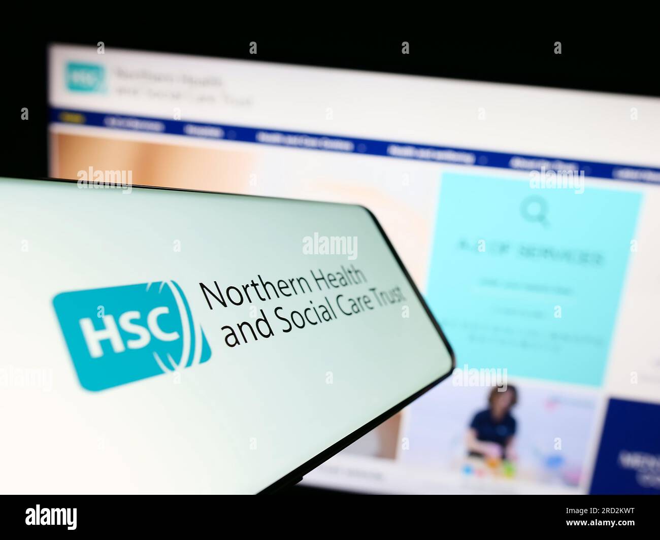 Cellphone with logo of Health and Social Care (HSC) in Northern Ireland on screen in front of website. Focus on center-left of phone display. Stock Photo