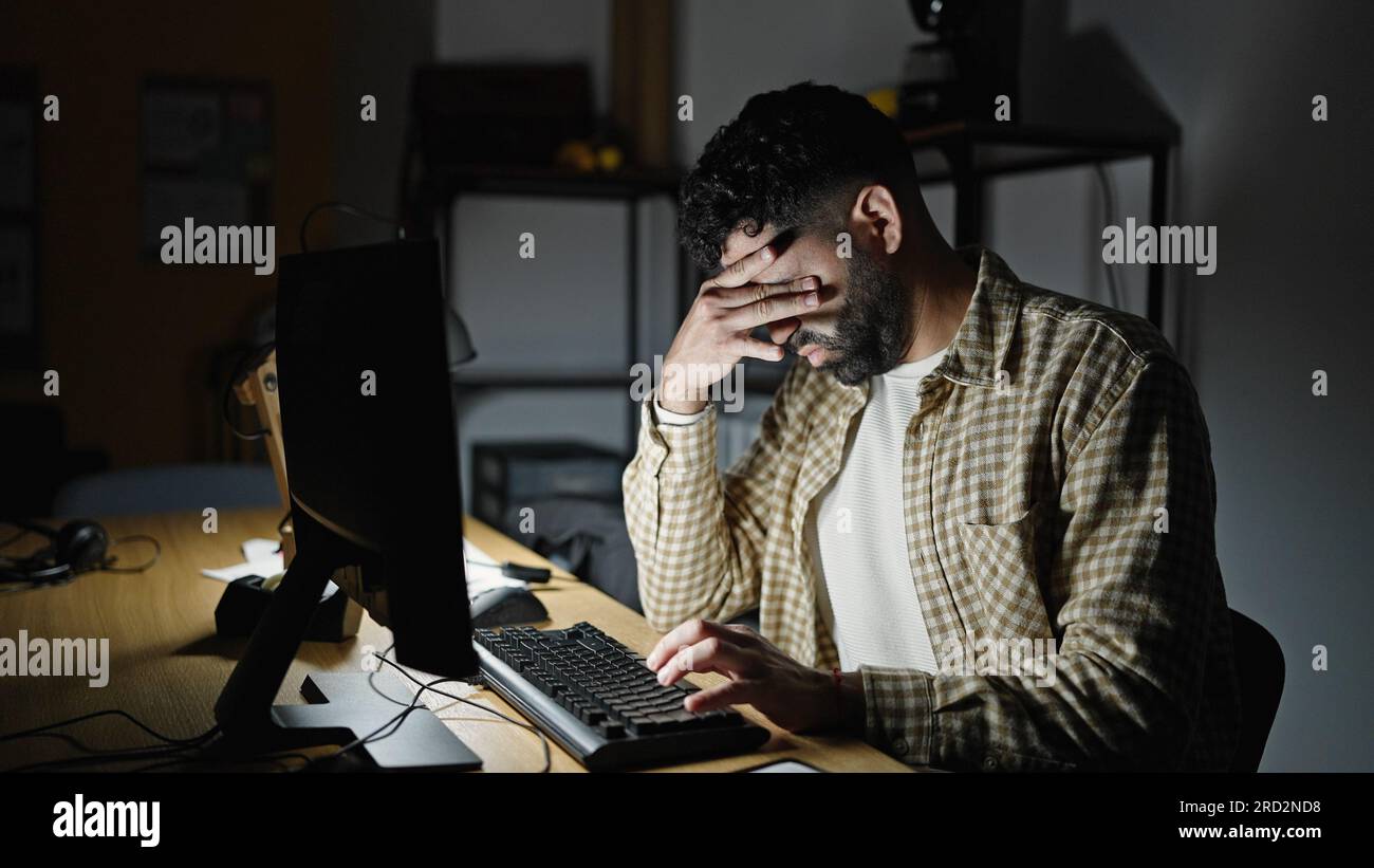 Young hispanic man business worker using computer stressed at office Stock Photo