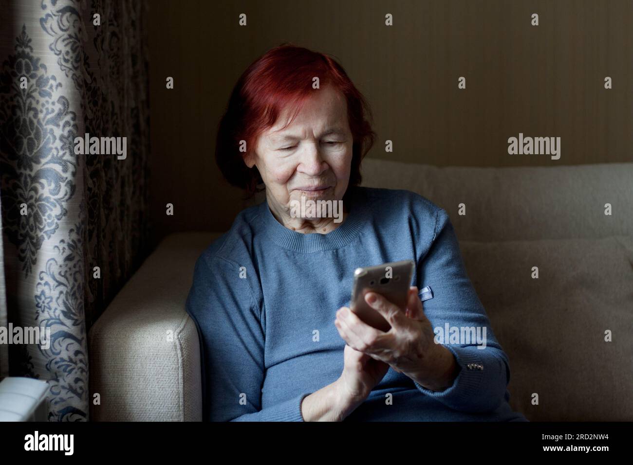 hands of an senior woman holding an old smartphone in her hands. Closeup, elderly man uses smartphone, touches screen of mobile phone with his finger. Stock Photo