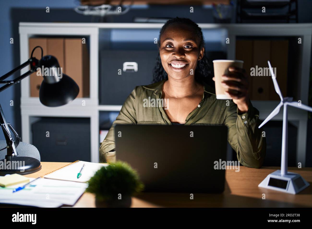 African woman working using computer laptop at night with a happy and ...