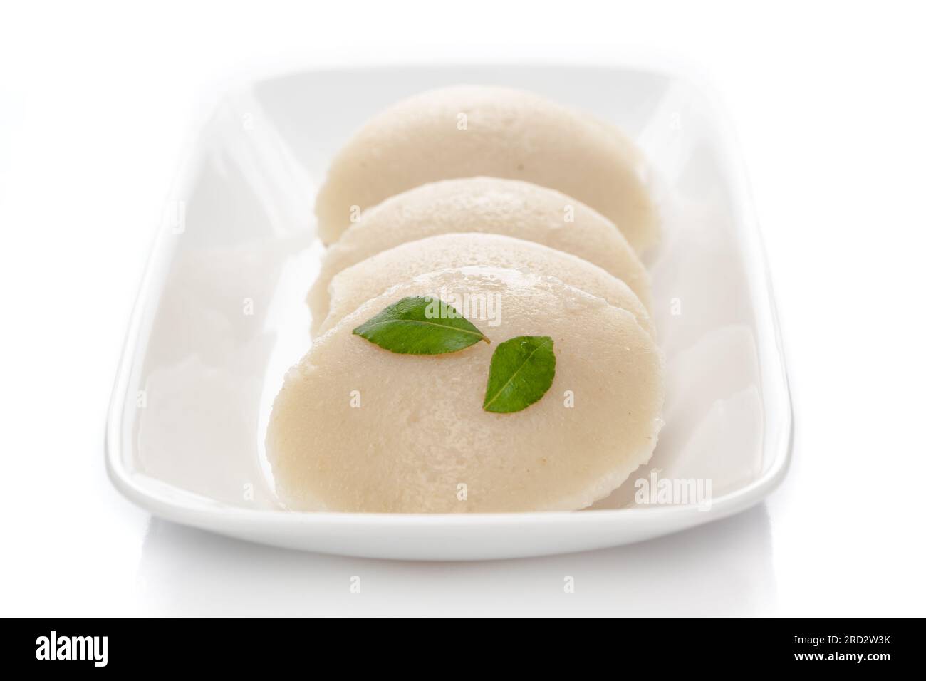 Close-up of fresh rava Idli or Idly with green curry leav is a popular south Indian food, served with coconut chutney. selective focus Stock Photo