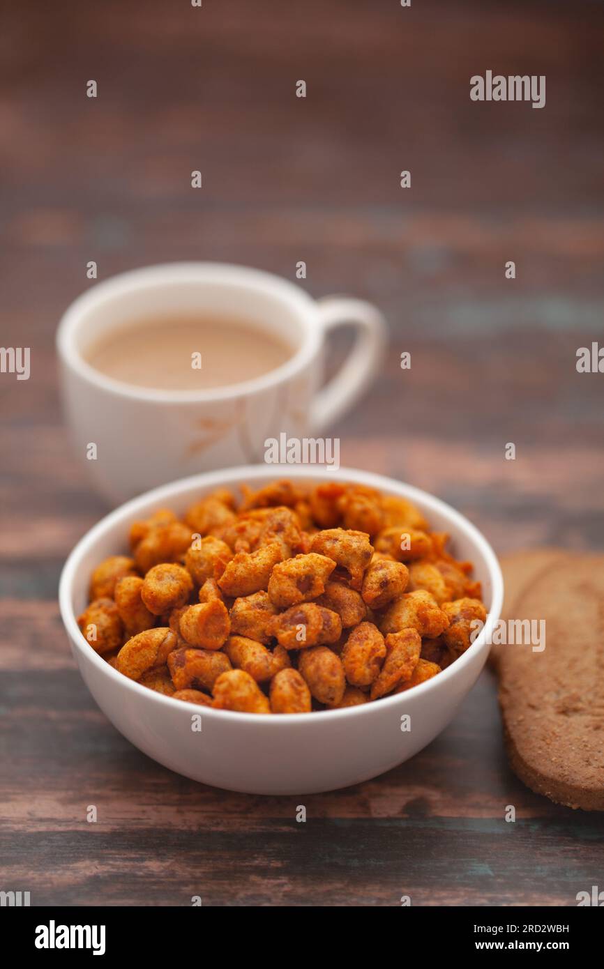 Close-Up of crunchy Indian mixture snacks with hot tea or Coffee time and handmade cookies (biscuits). Studio shoot at declined angle. Stock Photo
