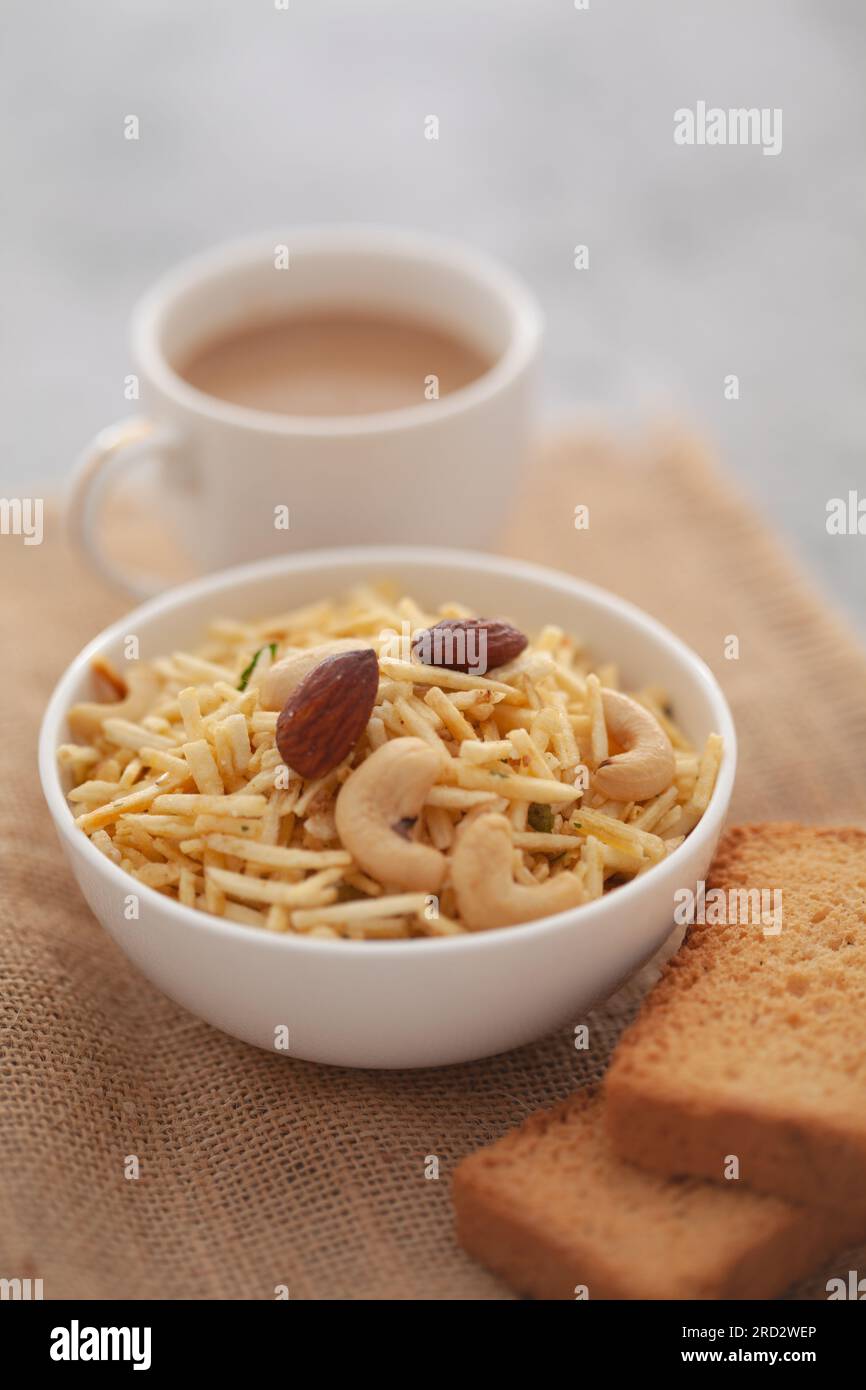 Close-Up of crunchy Indian mixture snacks with hot tea or Coffee time and handmade cookies (biscuits). Studio shoot at declined angle. Stock Photo