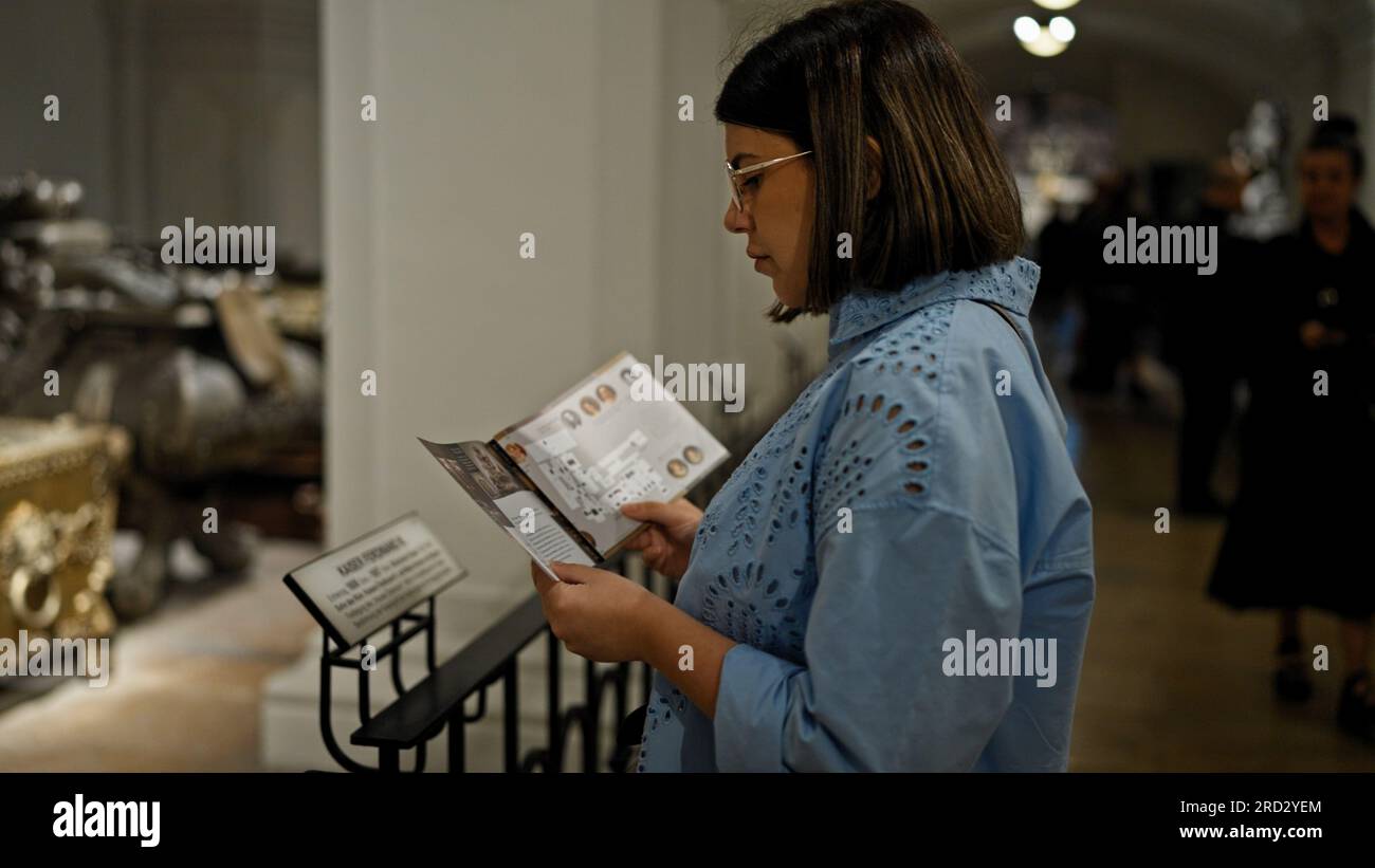 Young beautiful hispanic woman visiting crypt reading brochure at Imperial Crypt in Vienna Stock Photo