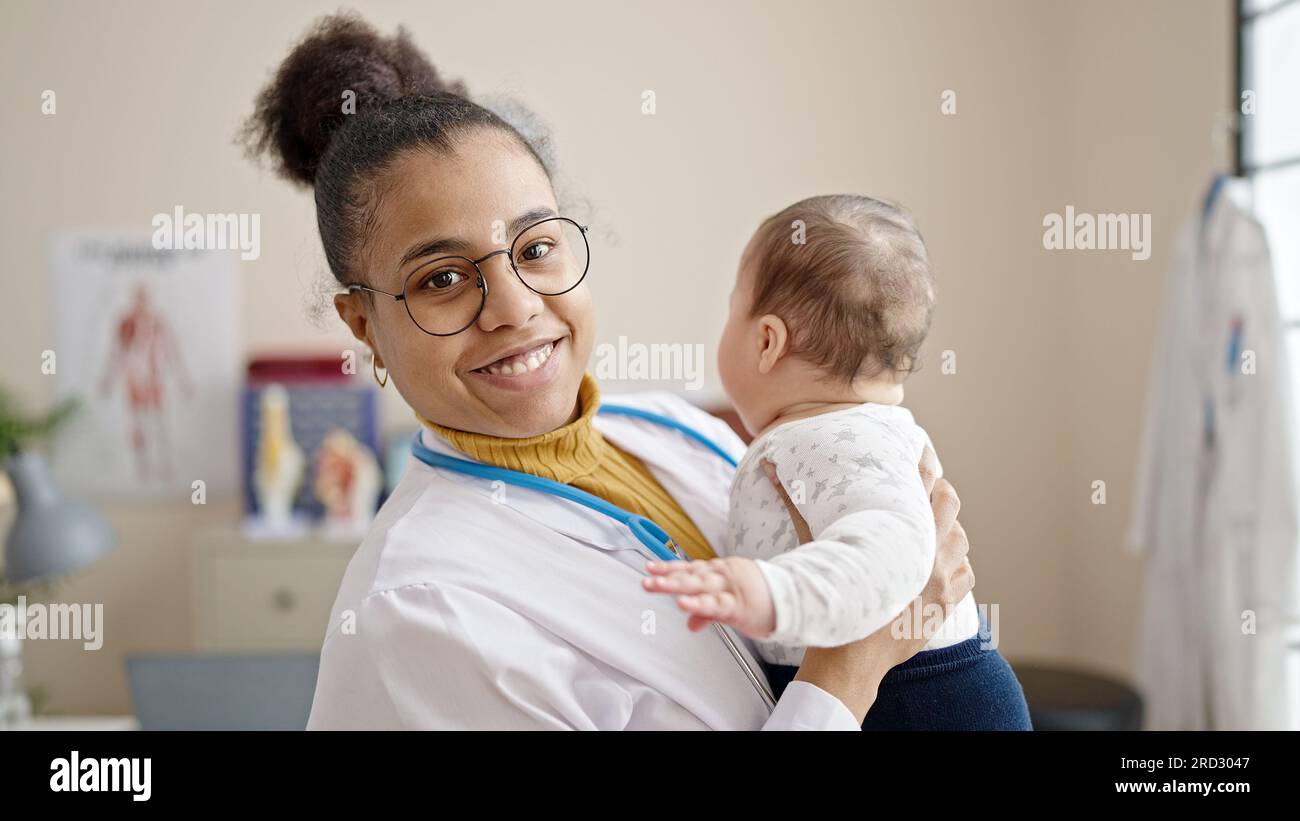 Mother and son doctor holding baby on arms at clinic Stock Photo