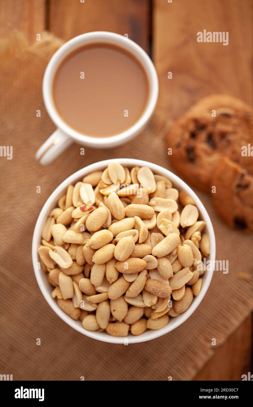 Close-Up of crunchy Indian peanuts snacks with hot tea or Coffee time and handmade cookies (biscuits). Studio shoot at declined angle. Stock Photo