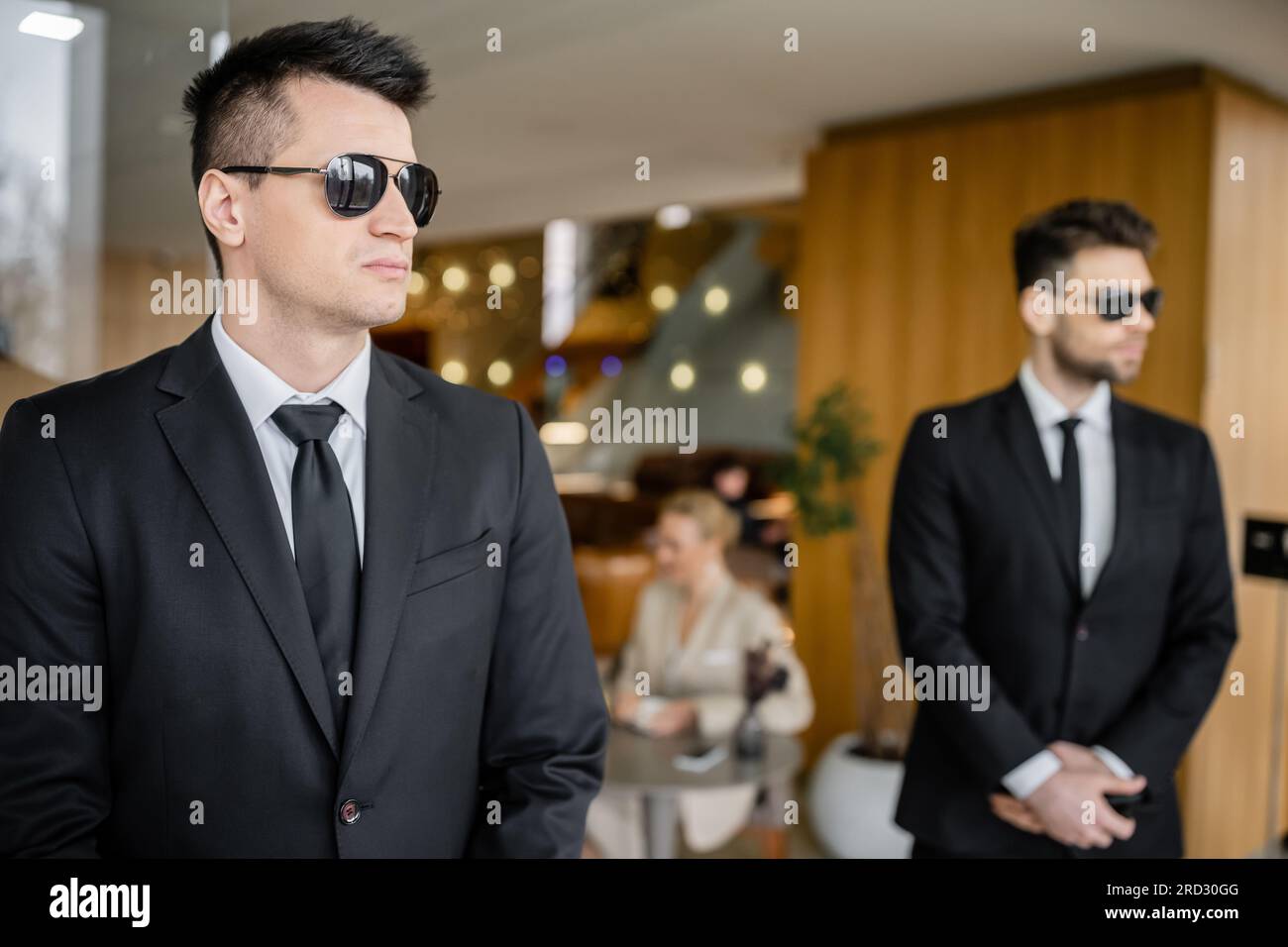 private security , personal safety service, handsome bodyguards in formal wear and sunglasses protecting safety of female client on blurred background Stock Photo