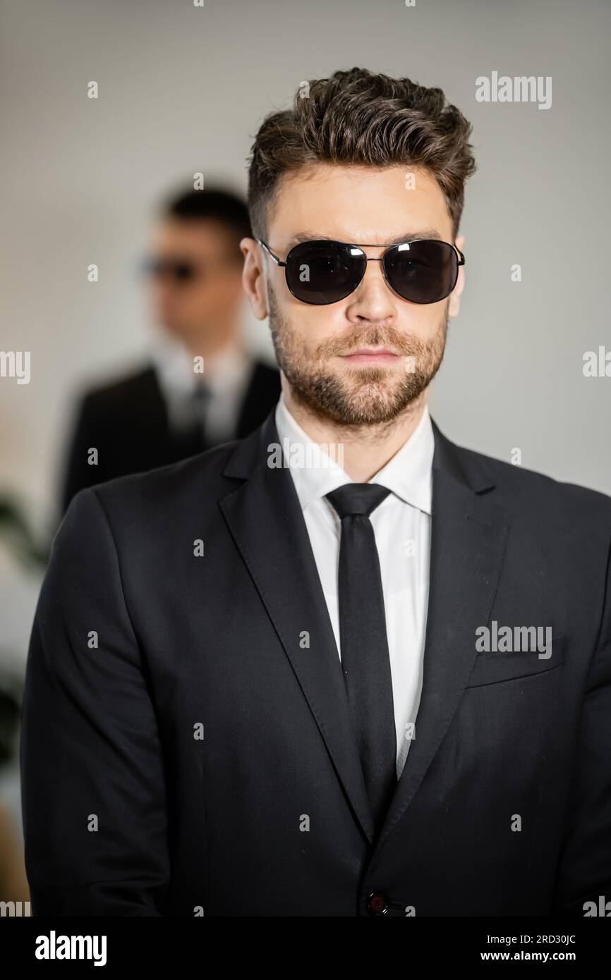 bodyguard service, handsome man in sunglasses and black suit with tie ...