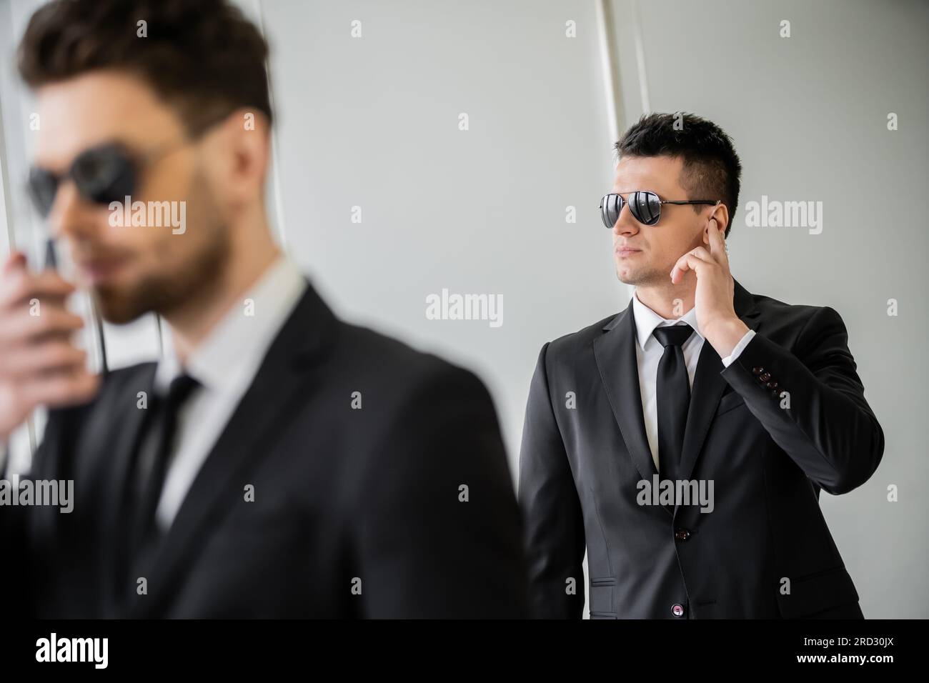 bodyguard communicating through earpiece, man in sunglasses and black