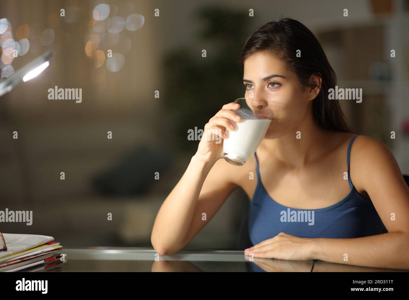 Woman in the night drinking milk at home looking away Stock Photo