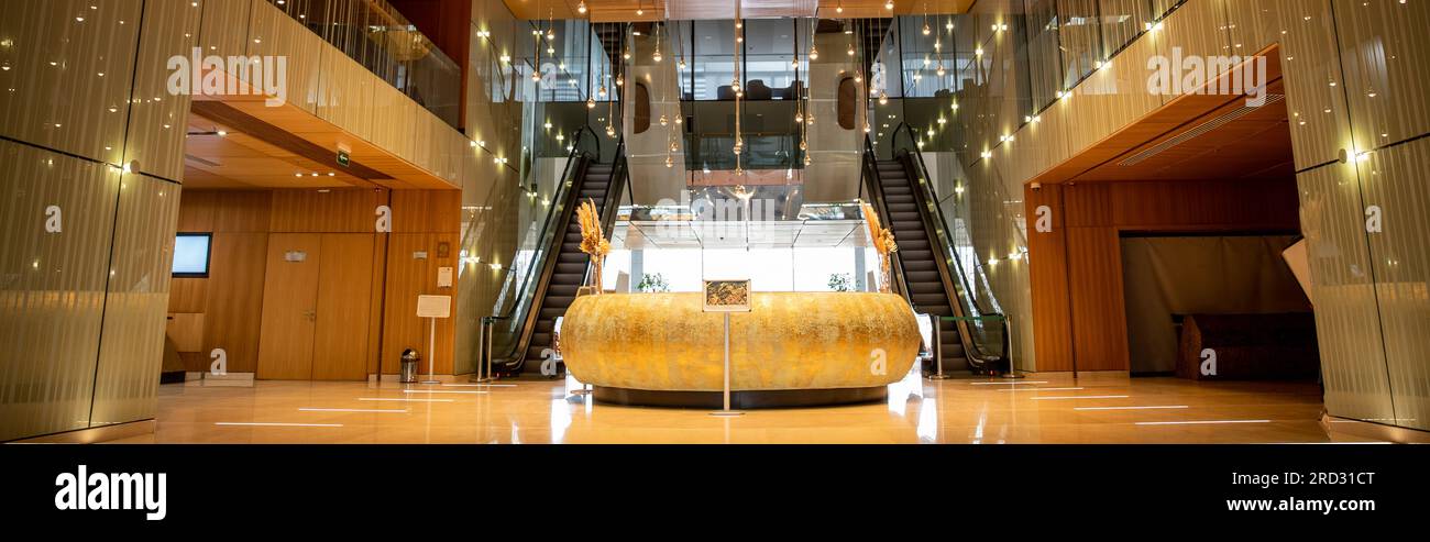 modern hotel interior with round reception desk and sophisticated lobby design, escalators, moving staircase, luxurious ambience, spacious and comfort Stock Photo