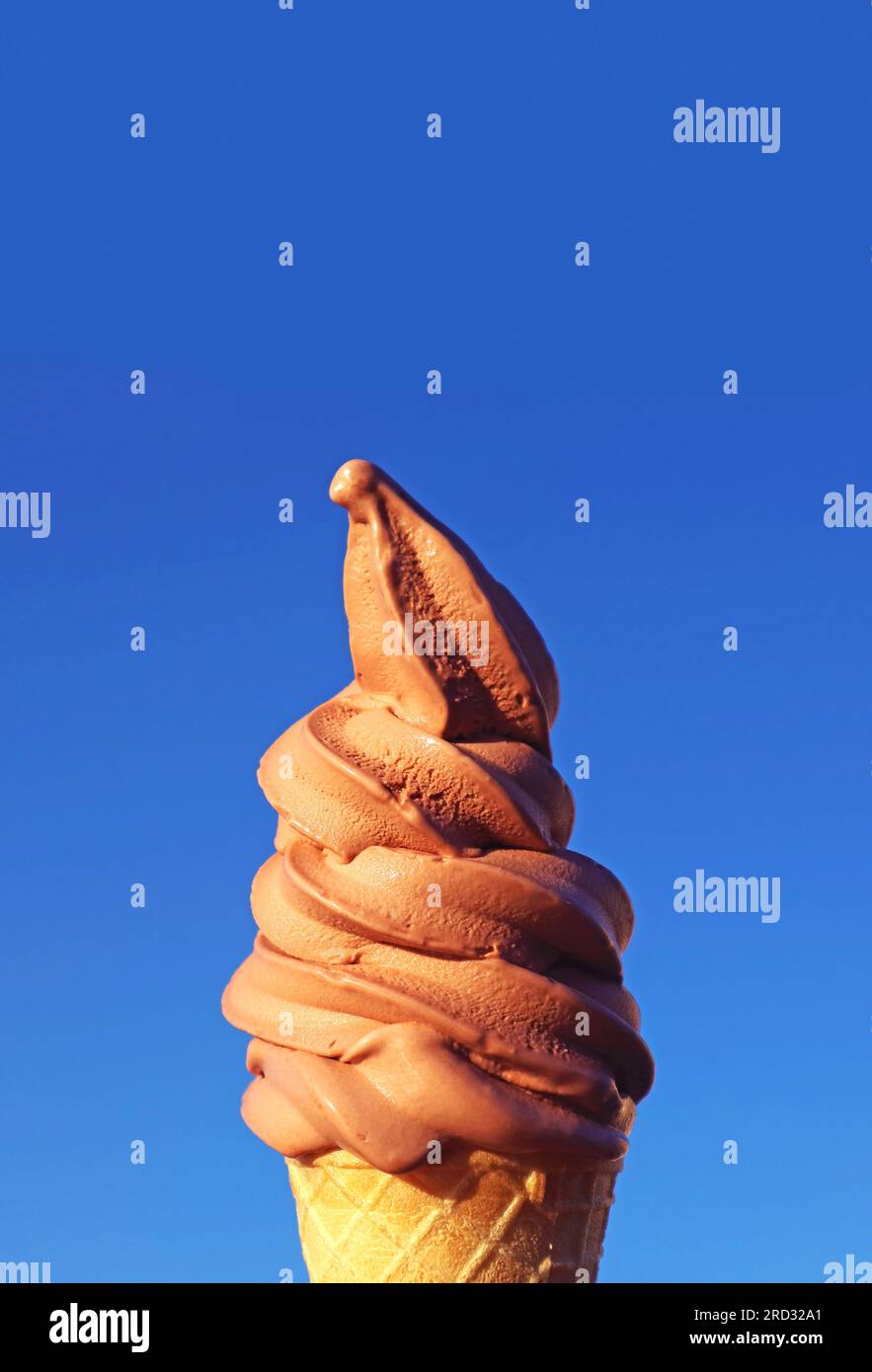 Chocolate Soft Serve Ice Cream Cone Against Sunny Vibrant Blue Sky