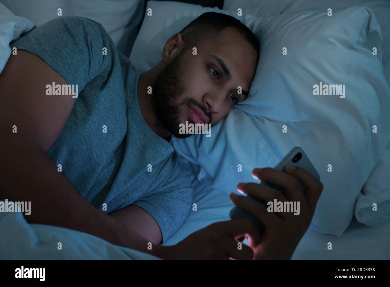 Young man using smartphone in bed at night. Internet addiction Stock Photo