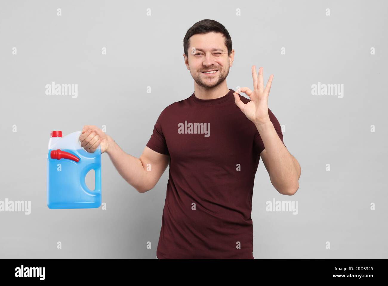 Man holding canister with blue liquid and showing OK gesture on light