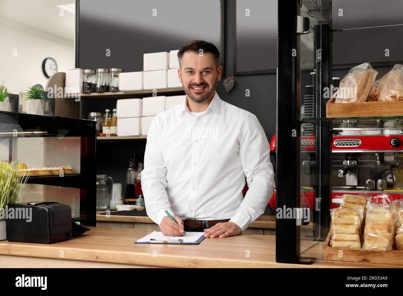 Business owner in his cafe. Man writing notes on clipboard near ...