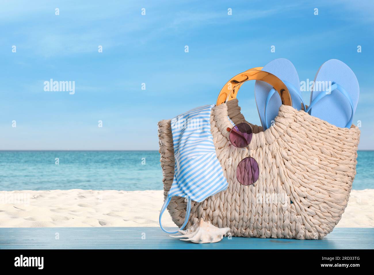 Bag with bikini and accessories on sunny ocean beach, space for text ...