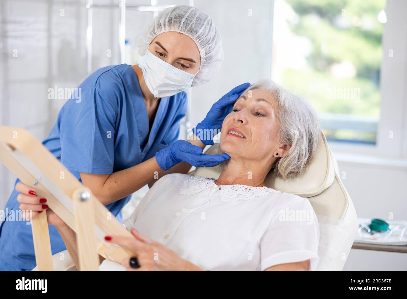 Mature patient with mirror, doctor with gloves Stock Photo Alamy