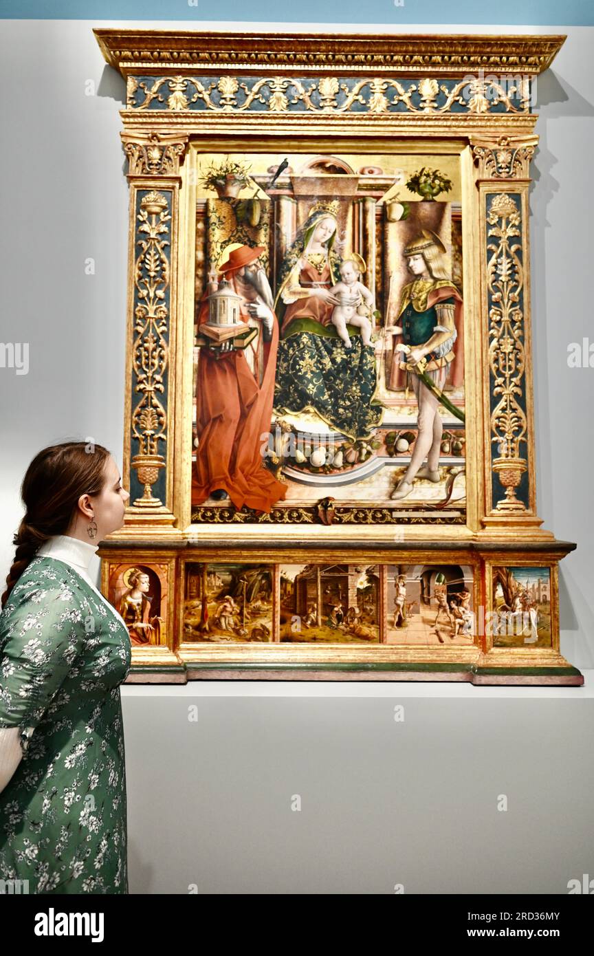 London, UK. The Carlo Crivelli altarpiece viewed by a gallery worker