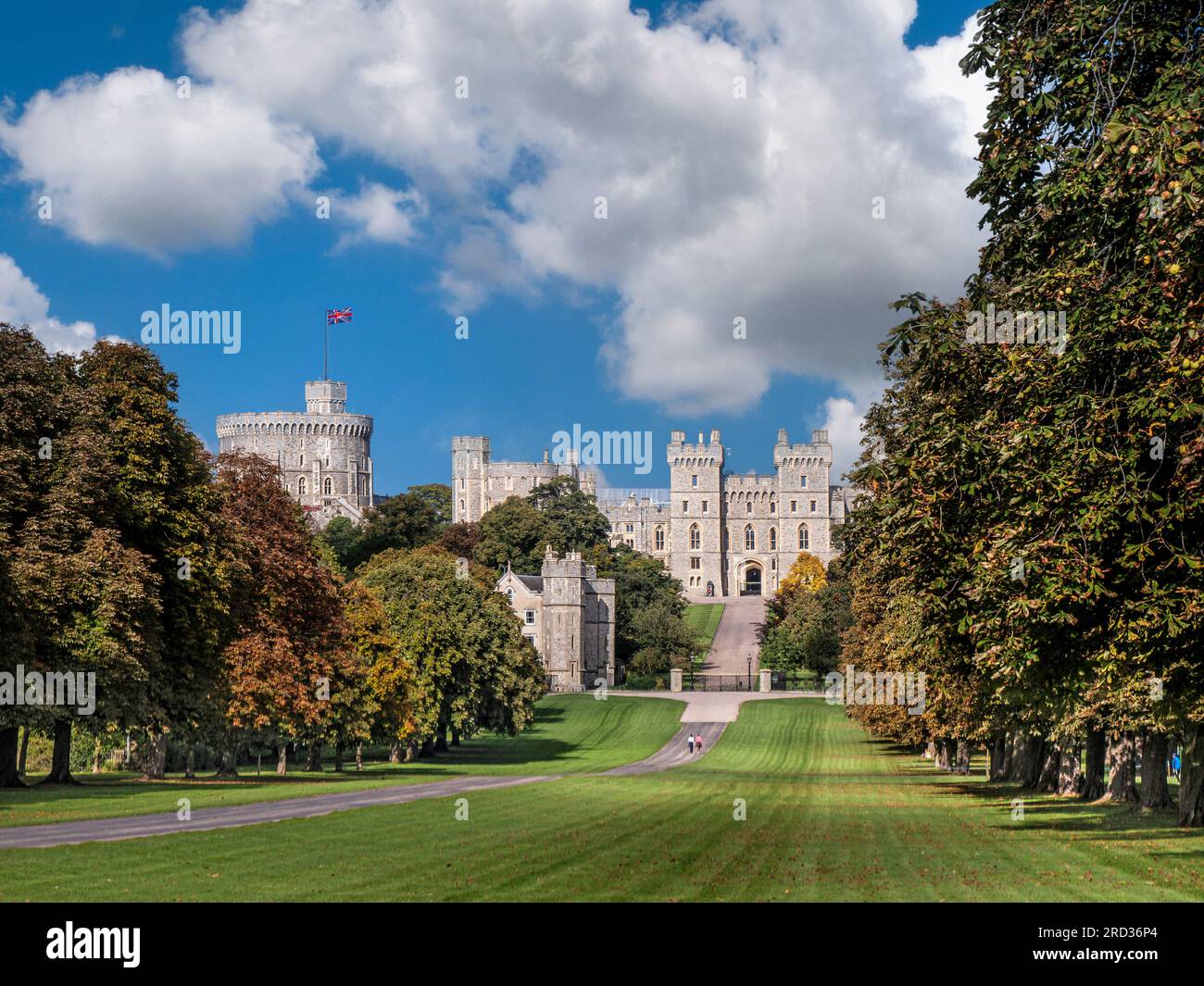 Windsor Castle and the Long Walk with Union Jack flag, in summer/autumn colour with walkers in dappled sunlight blue sky & clouds Windsor Berkshire UK Stock Photo