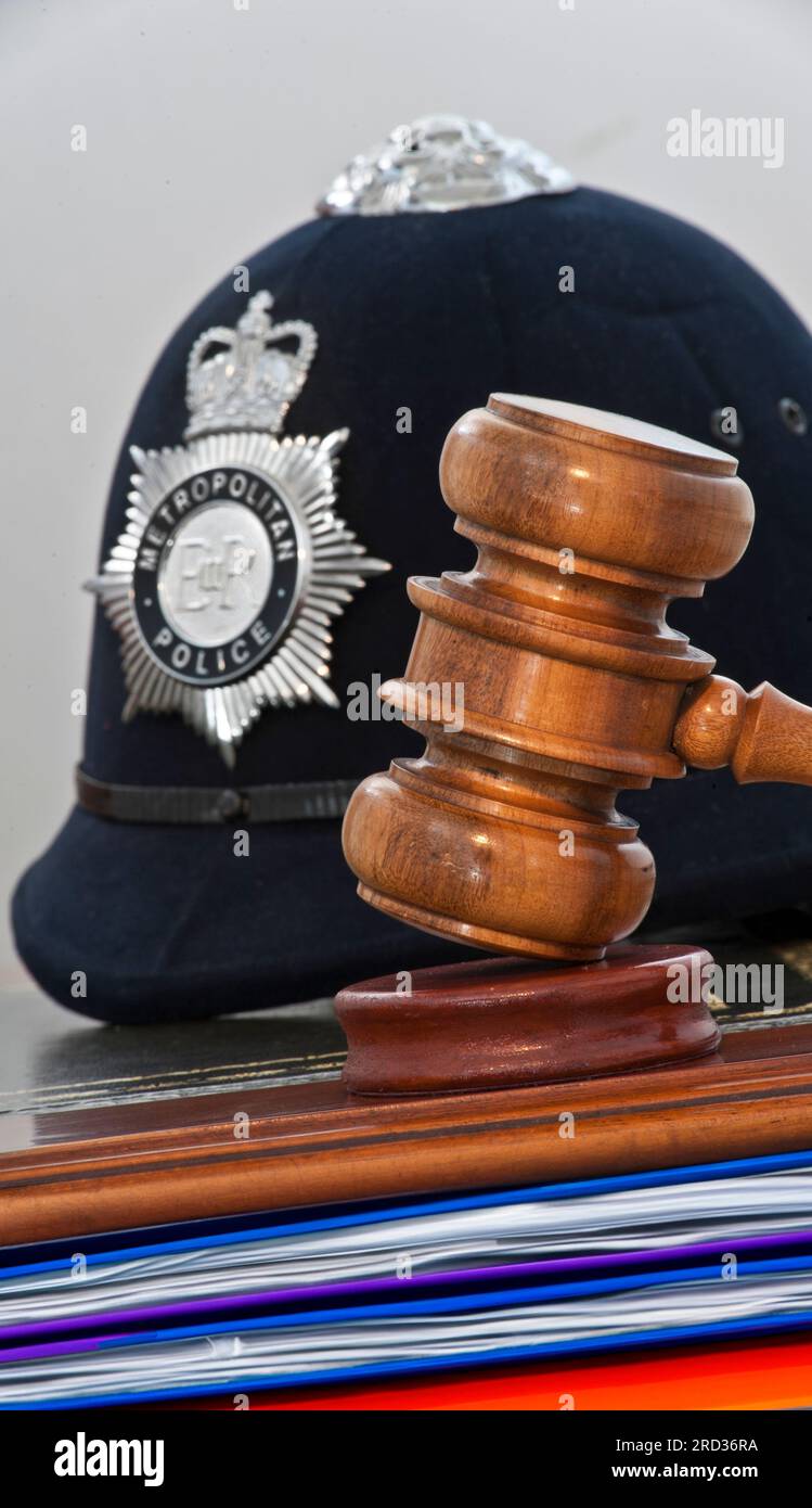 POLICE EVIDENCE GAVEL COURT OATH JUDGEMENT Legal concept Metropolitan Police helmet with judges gavel hammer in London law courts concept UK Stock Photo