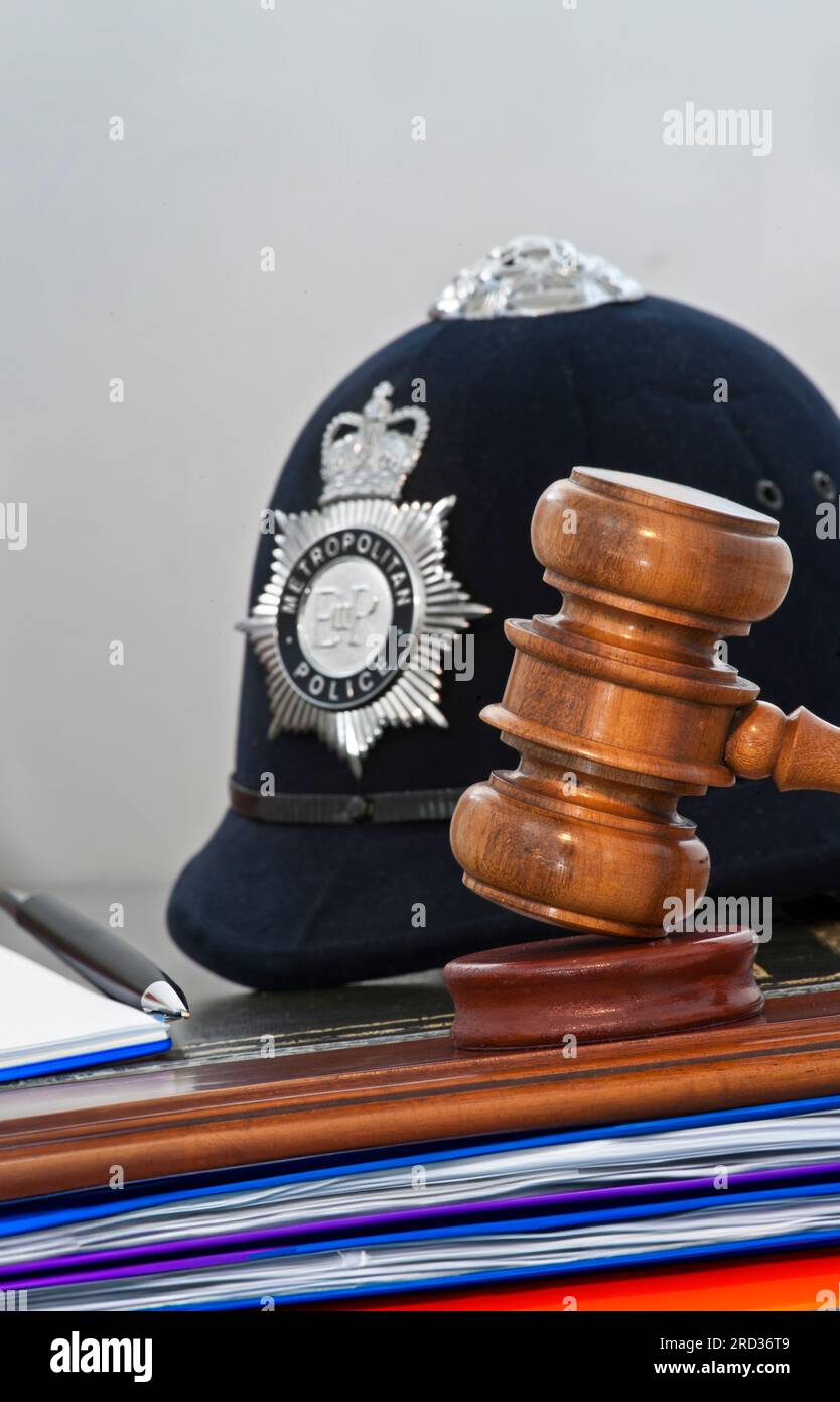 POLICE EVIDENCE GAVEL COURT OATH NOTEBOOK PEN JUDGEMENT Legal concept Metropolitan Police helmet with judges gavel in London law courts situation UK Stock Photo