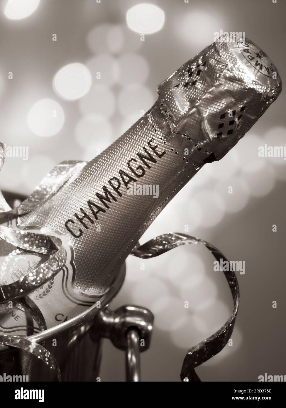 CHAMPAGNE BOTTLE RETRO ERA VINTAGE B&W PARTY LIGHTS  on ice in wine cooler champagne ice bucket, party streamers & sparkling style celebration lights Stock Photo