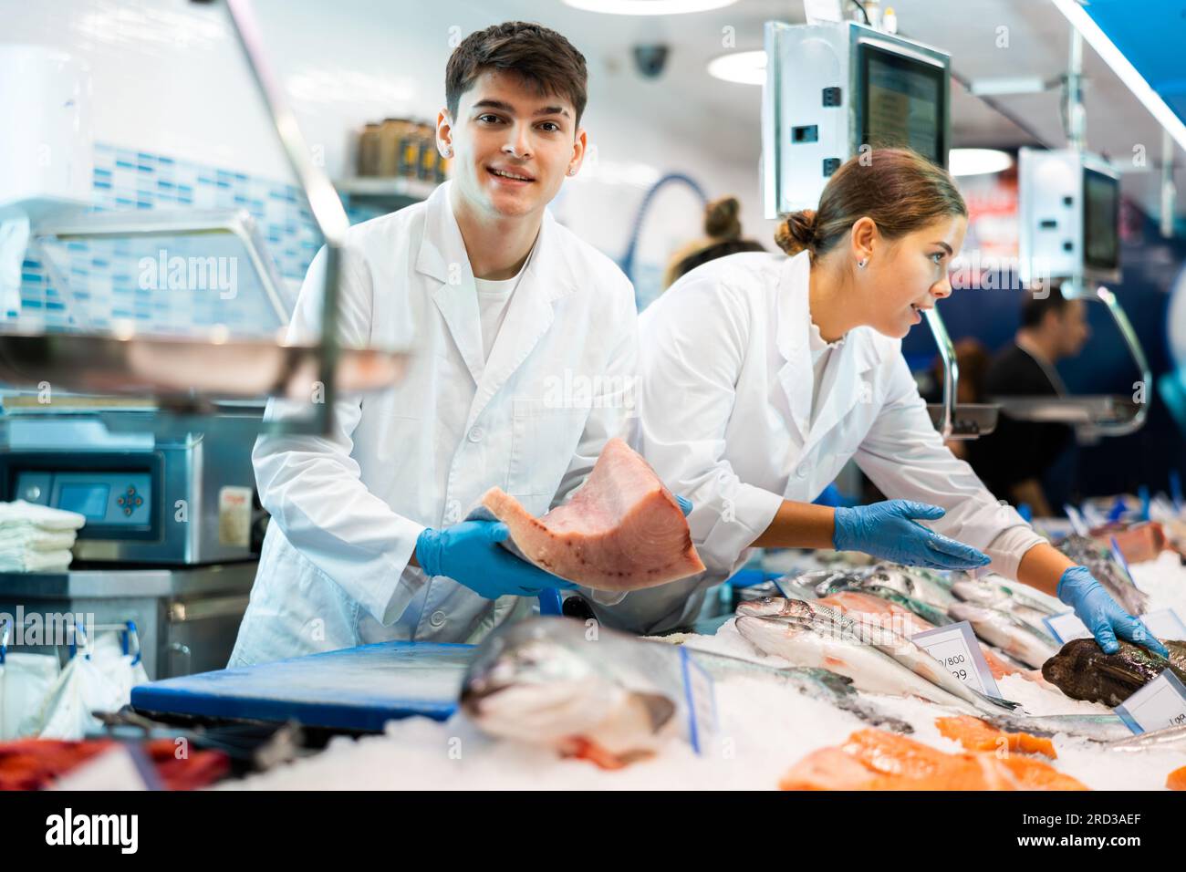 Positive salesman demonstrating tuna in fish store Stock Photo - Alamy