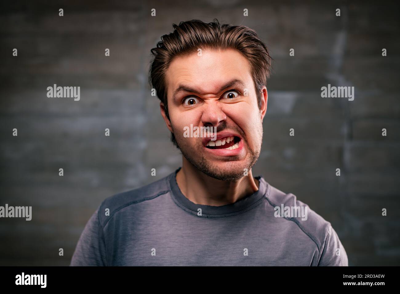 Young crazy man emotional portrait on gray wall background Stock Photo