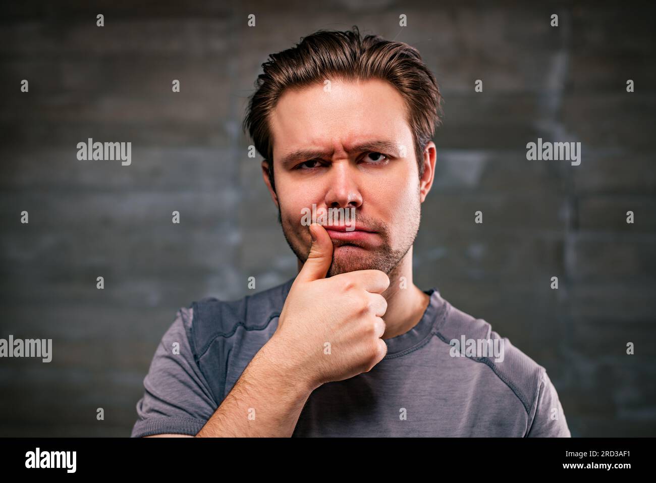 Young pensive man portrait on gray wall background Stock Photo