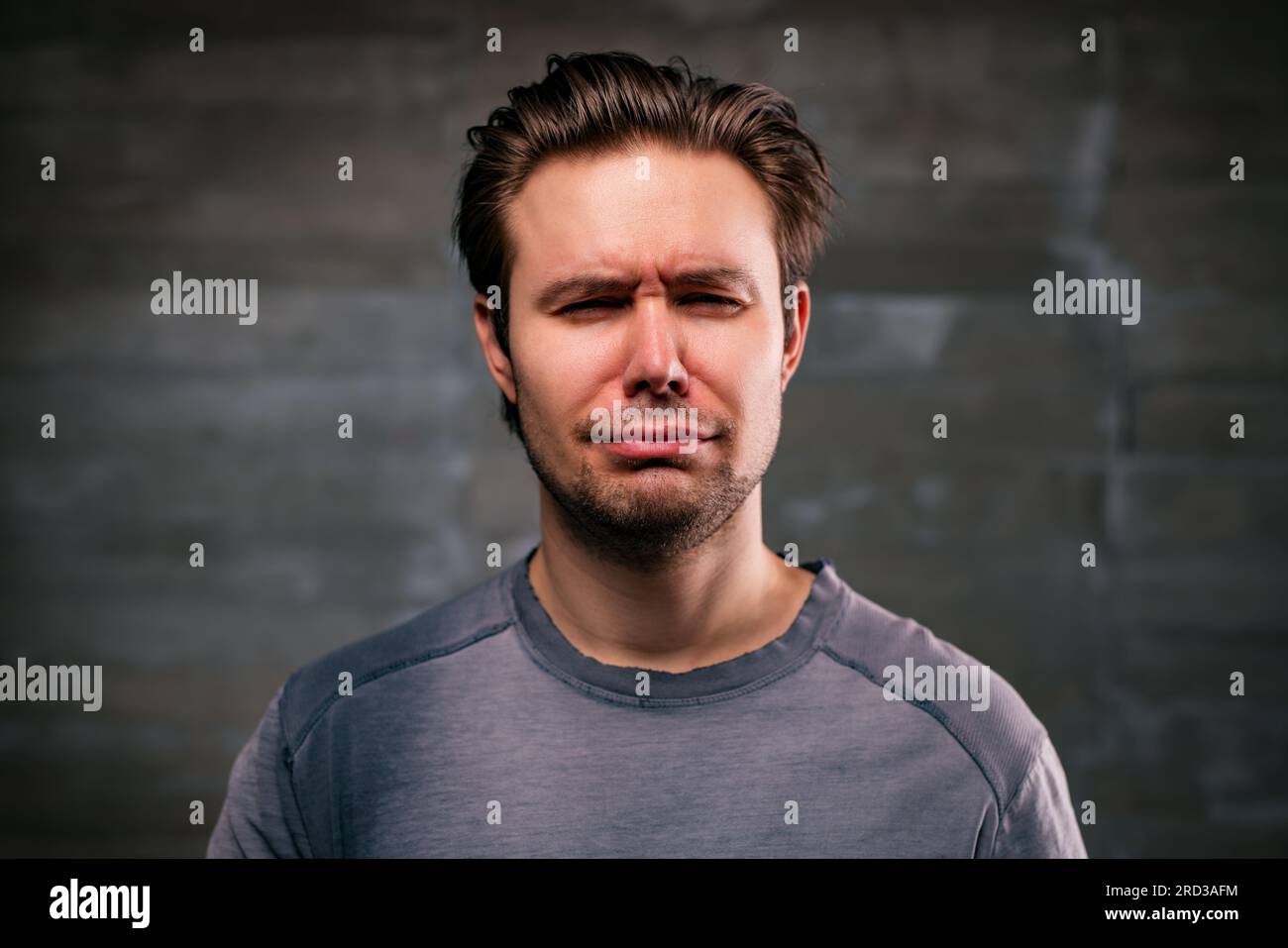 Young handsome man crying portrait on gray wall background Stock Photo