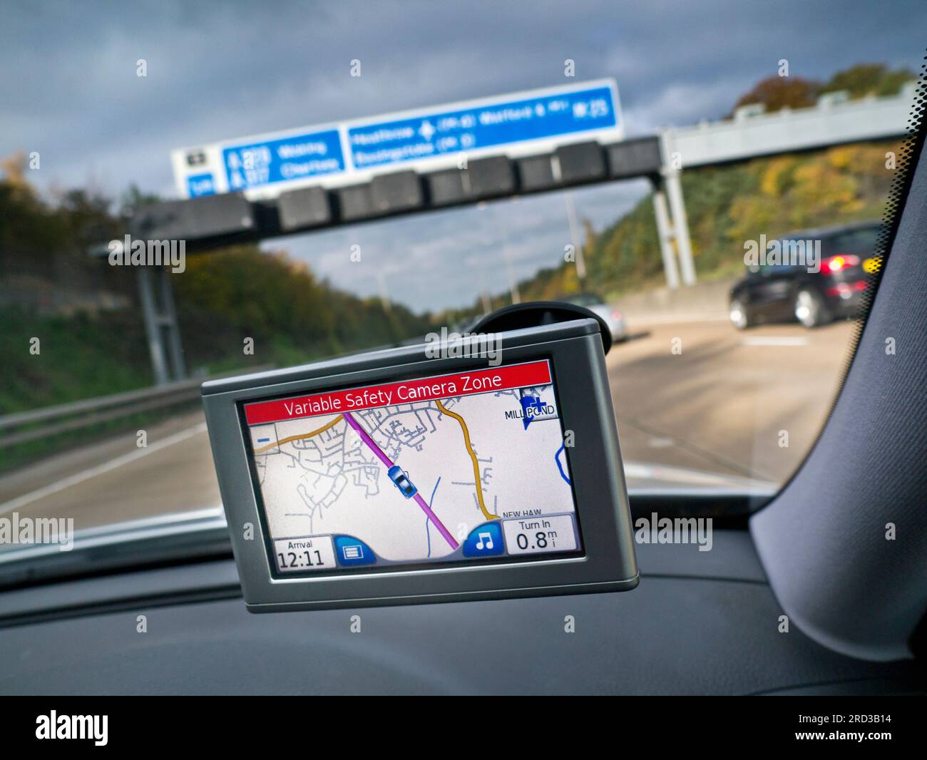 Satellite Navigation SAT NAV GPS screen in-car windscreen mounted, on M25 Orbital motorway with red 'Variable Safety Camera Zone' alert speed warning displayed Surrey UK Stock Photo