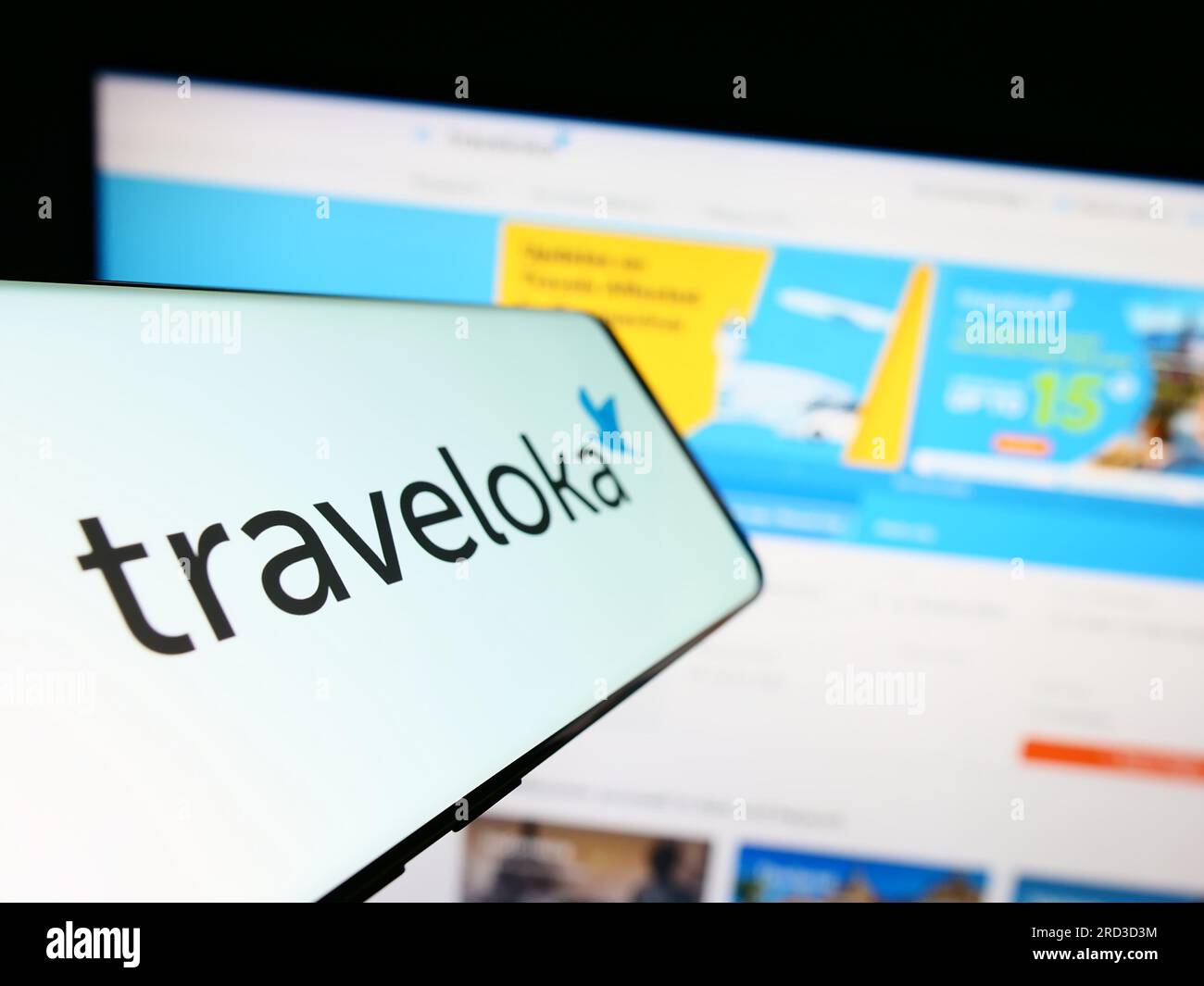Smartphone with logo of Indonesian travel company Traveloka on screen in front of business website. Focus on center-left of phone display. Stock Photo